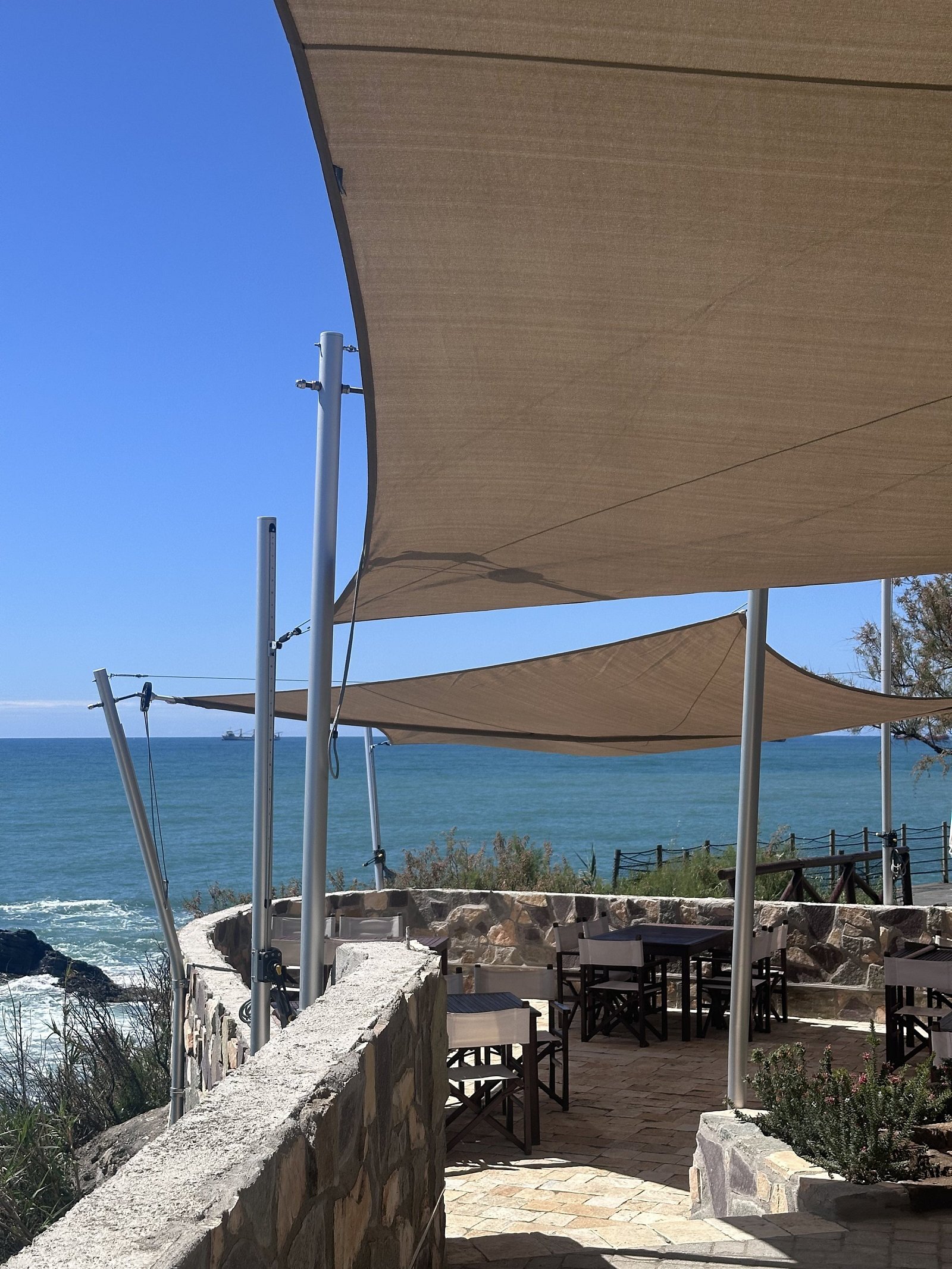 Bagni Sama, Antignano: le vele sopra la terrazza del ristorante e il muro in pietra sul mare
